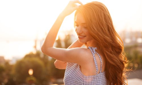 Close up side view of ginger woman in dress posing on the sunset
