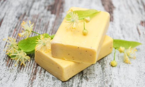 Handmade soap and linden flowers on a wooden table